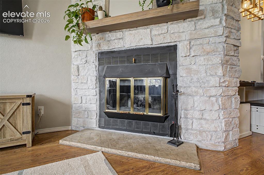Image 10 of 42: Stacked stone fireplace featuring a wood mantel