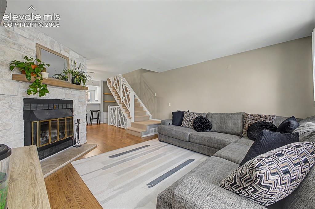 Image 11 of 42: Living room featuring a stacked stone fireplace with a wood mantle, wood-fi