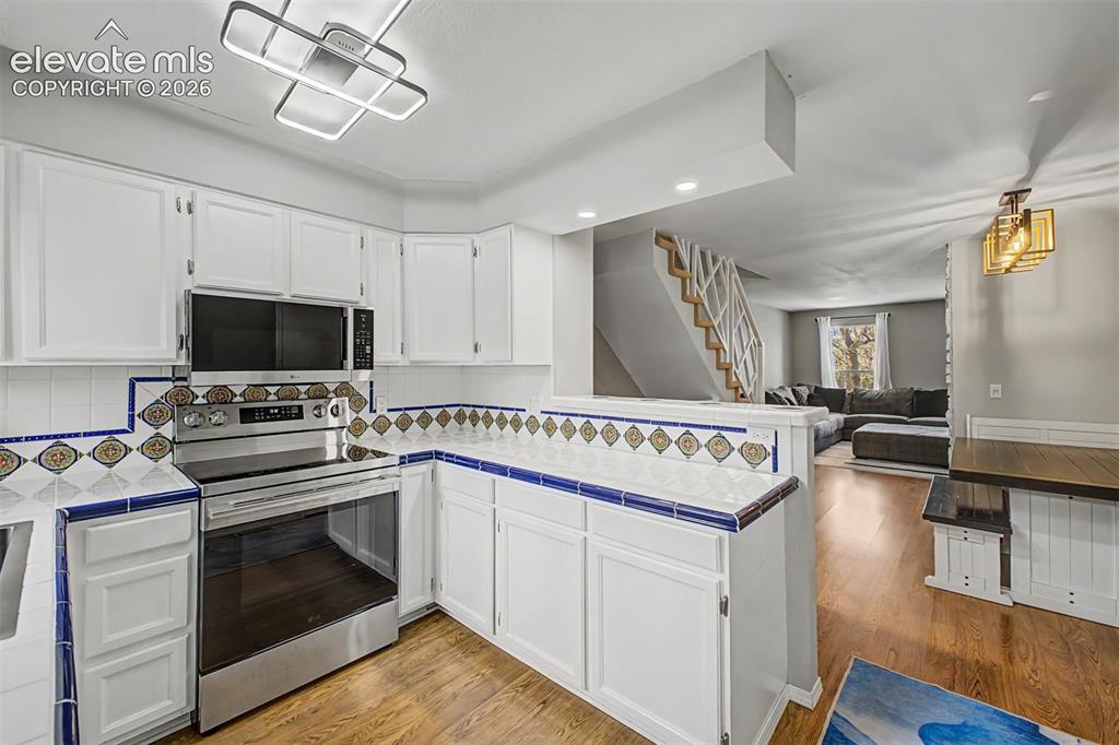 Image 16 of 42: Kitchen featuring white cabinetry, decorative tile countertops, a stainless
