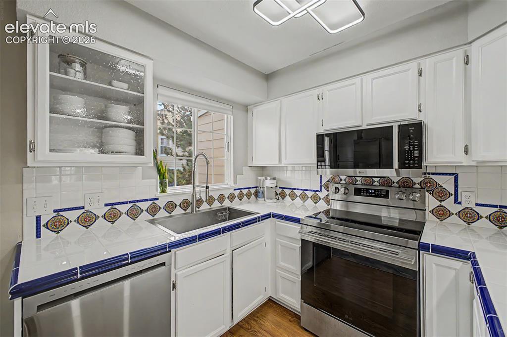 Image 18 of 42: Kitchen featuring white cabinetry, tile countertops with decorative accents