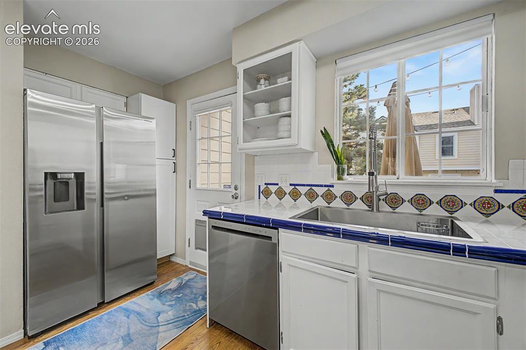 Image 20 of 42: Kitchen featuring stainless steel appliances, white cabinetry, a tiled coun