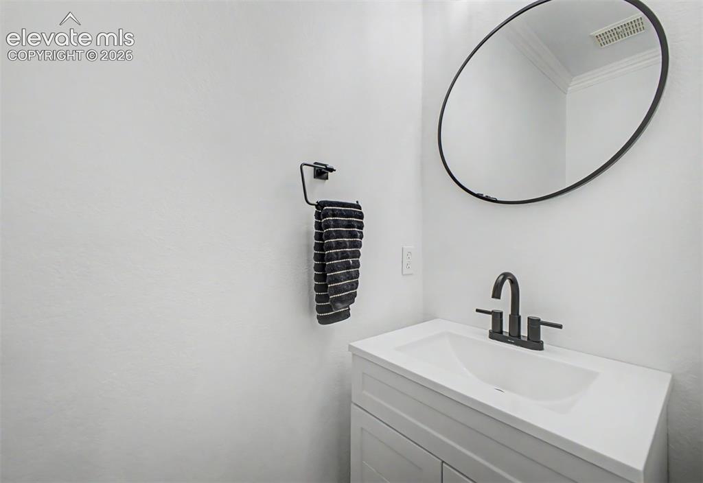 Image 21 of 42: Powder room vanity with matte black faucet, oval mirror, and white countert