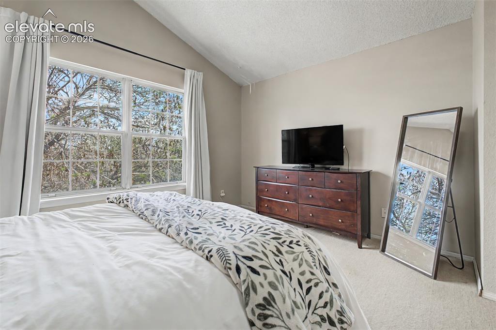 Image 23 of 42: Bedroom featuring a vaulted ceiling and wall-to-wall carpeting