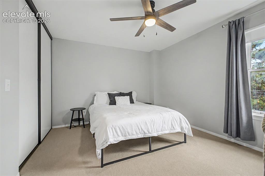 Image 25 of 42: Carpeted bedroom with a window, ceiling fan, and sliding closet doors