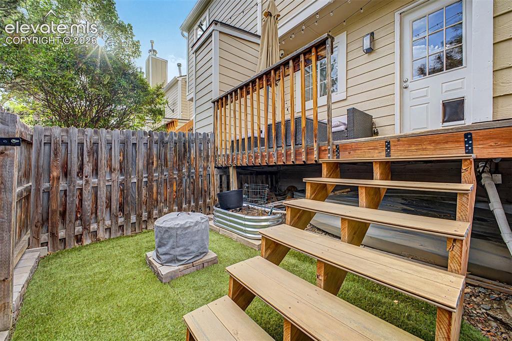Image 34 of 42: Rear exterior deck with wooden railing and stairs, a privacy fence, and a l