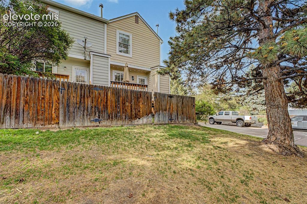 Image 36 of 42: Rear exterior featuring a wooden privacy fence, upper-level balcony, and ma