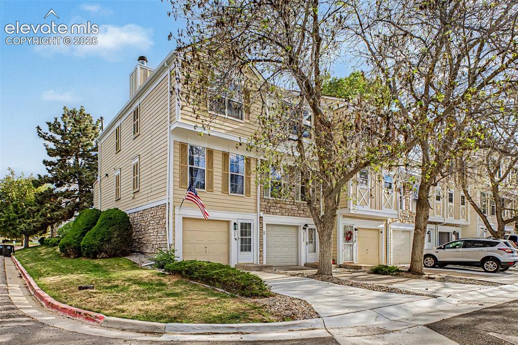 Image 4 of 42: Multi-level townhouse featuring light-colored siding, stone facade accents,
