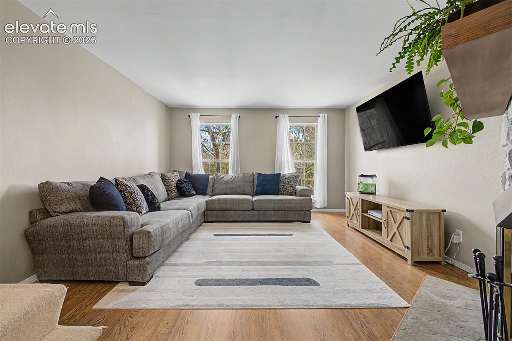 Image 8 of 42: Living area with wood-finish flooring, light-toned walls, and a large area