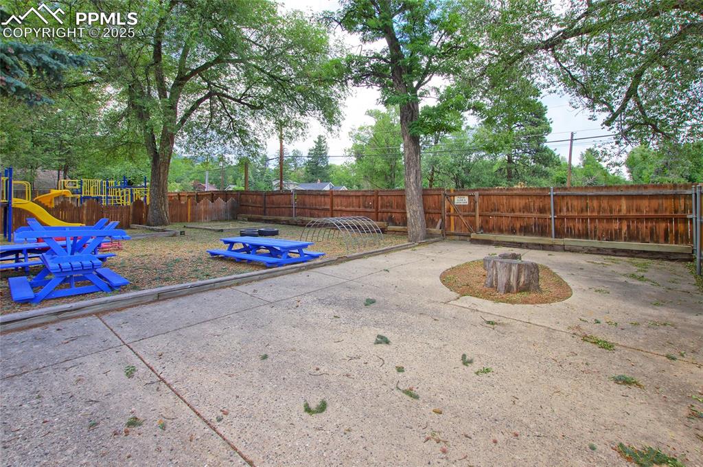 Image 27 of 34: Fenced backyard with a playground