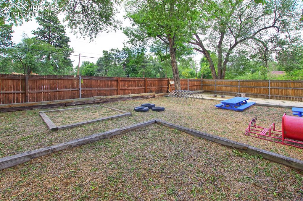 Image 28 of 34: Fenced backyard featuring a vegetable garden