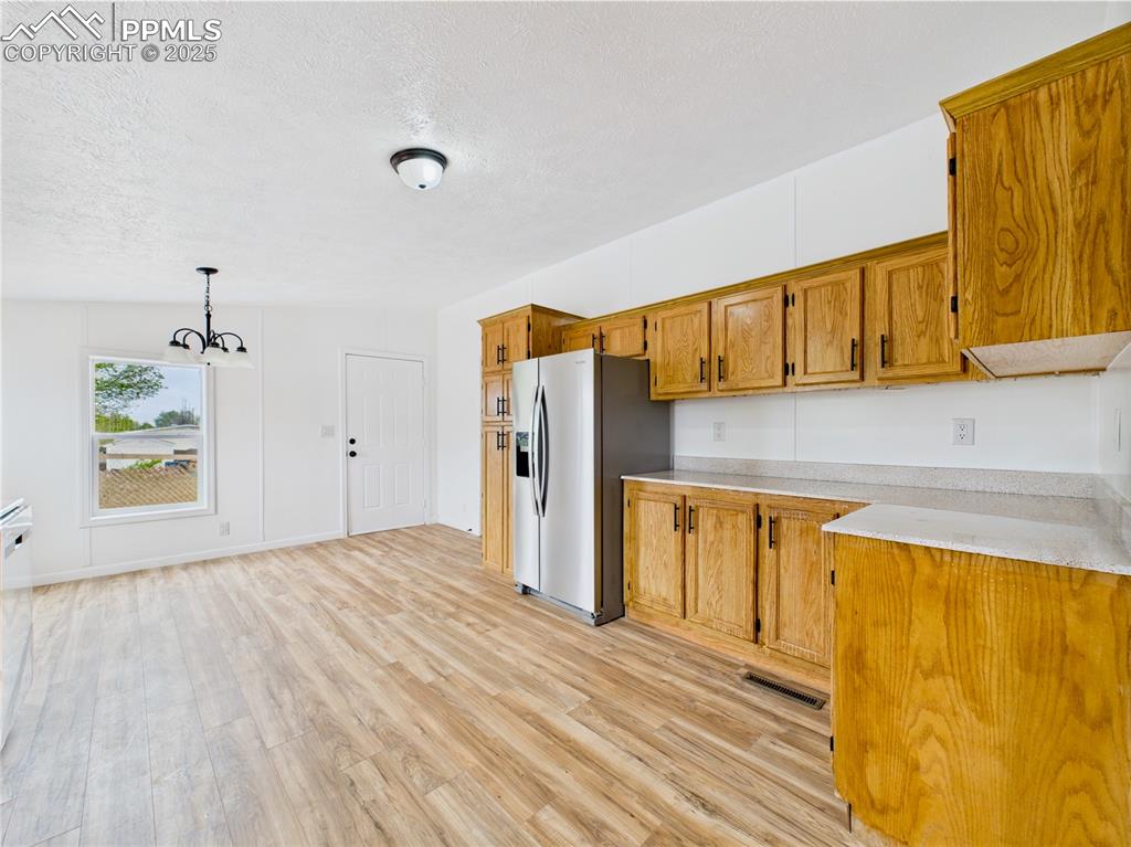 Image 13 of 44: Charming kitchen/dining space with light-toned countertops, stylish chandel