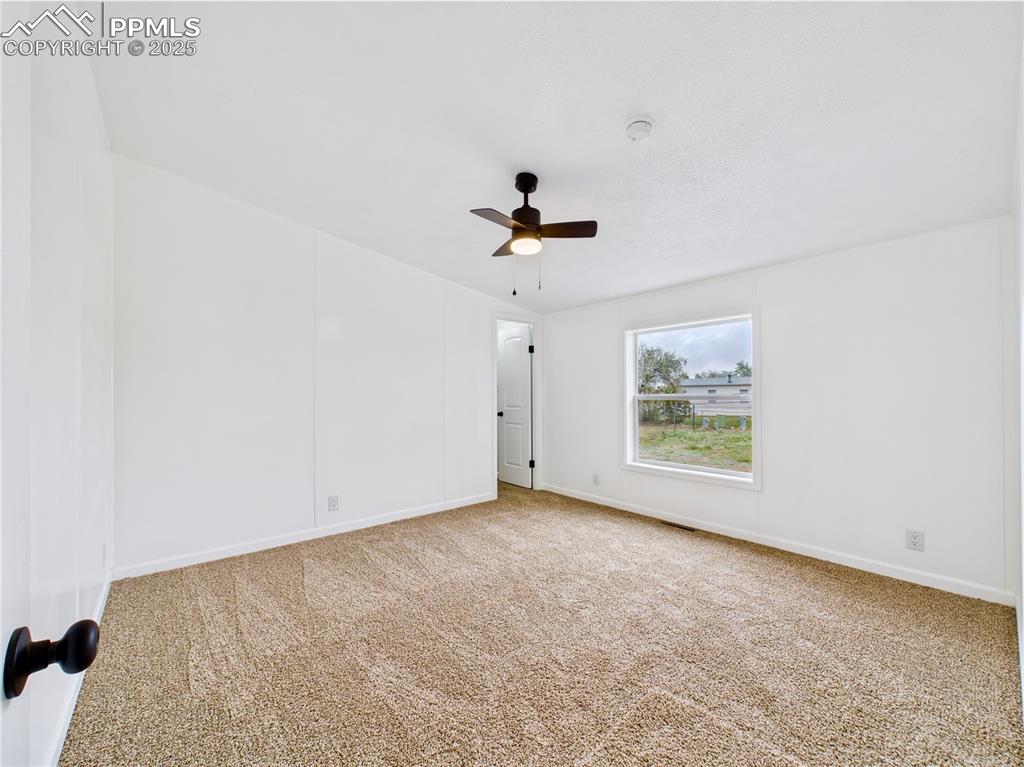 Image 22 of 44: Light and airy bedroom boasting a private bath, ceiling fan, and plush ligh