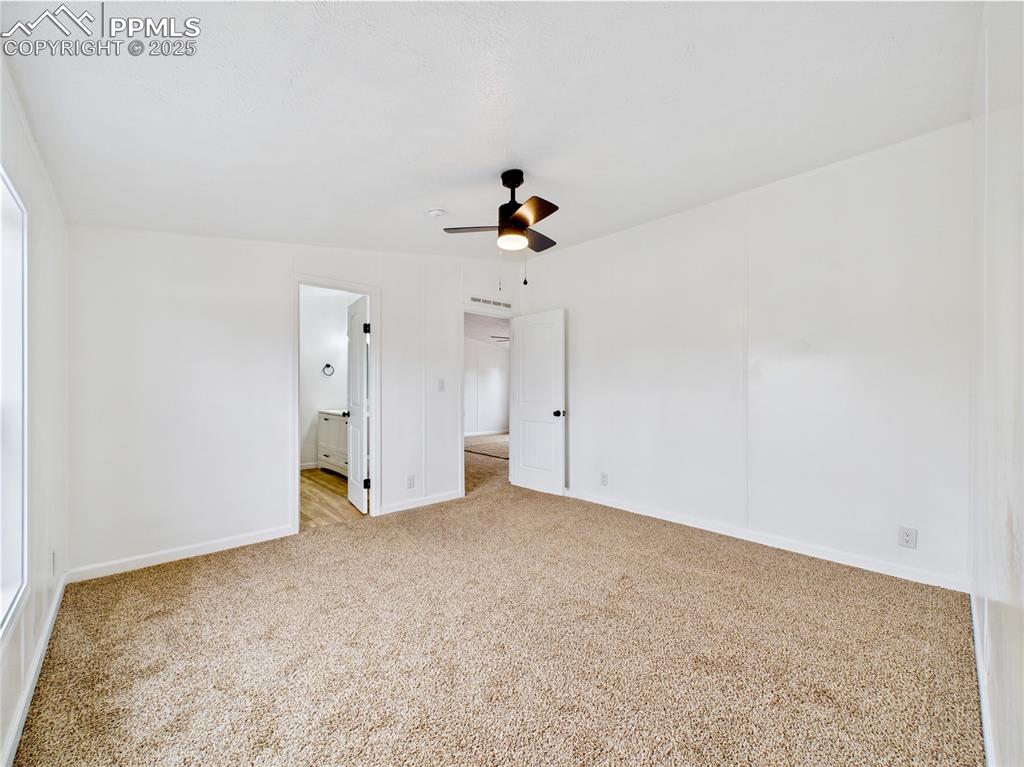 Image 24 of 44: Light and airy bedroom boasting a private bath, ceiling fan, and plush ligh
