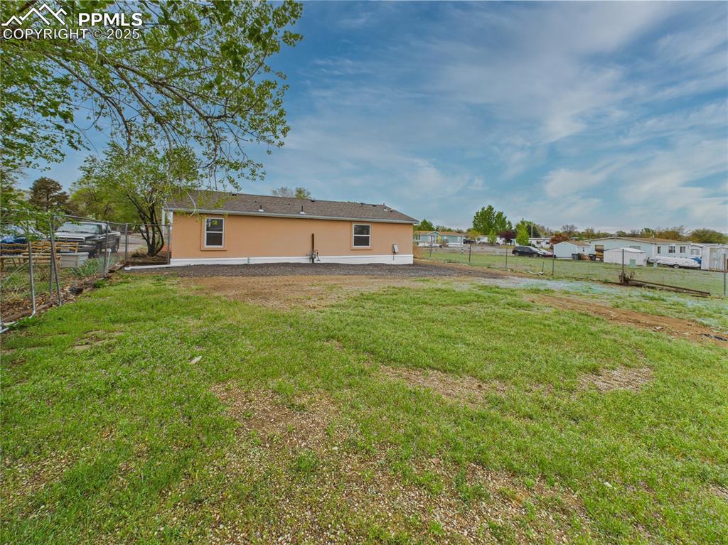 Image 42 of 44: Generous backyard with room to play or garden, highlighted by stucco siding