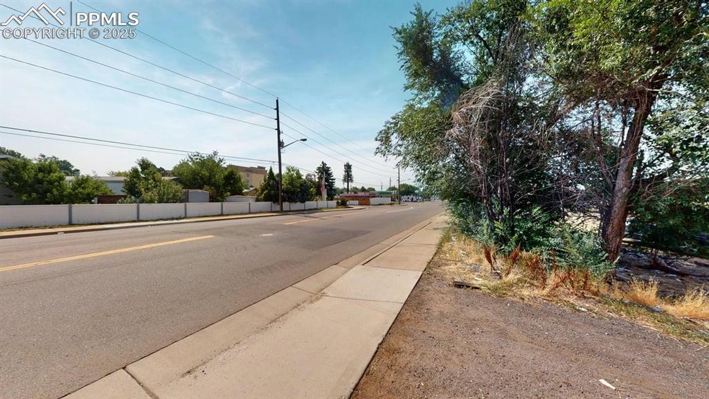 Image 3 of 4: View of asphalt road featuring sidewalks, street lights, and curbs