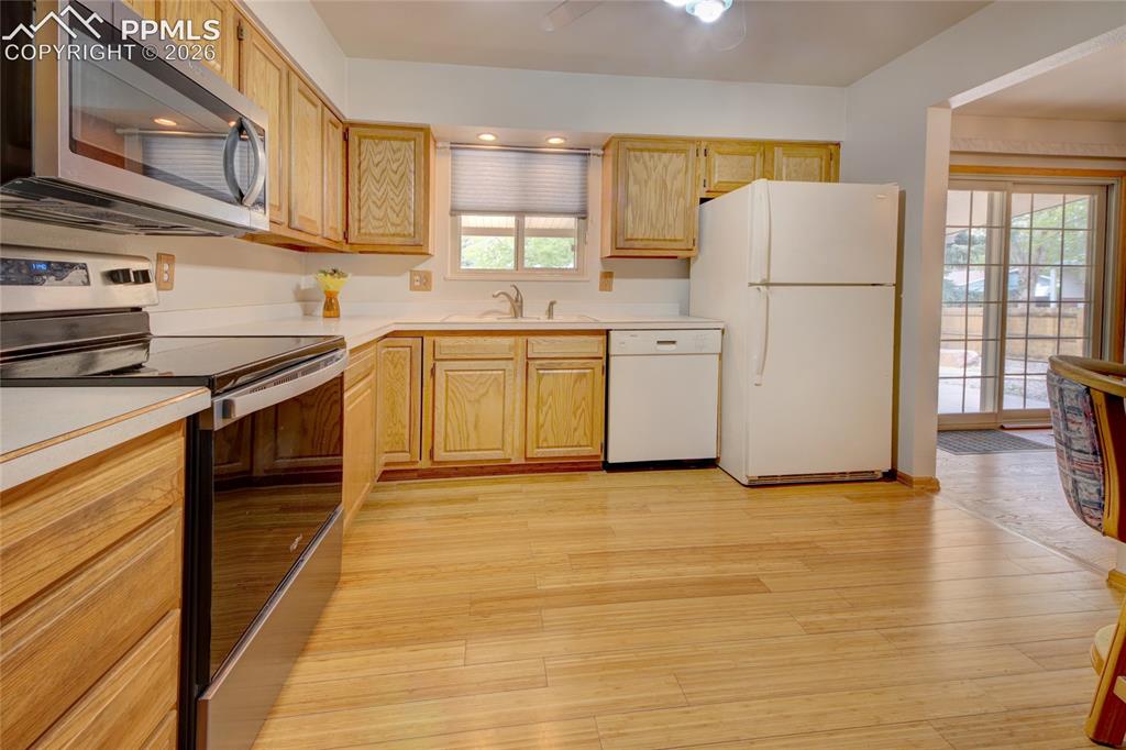 Image 13 of 33: Kitchen featuring wood-finish flooring, light wood cabinetry, stainless ste