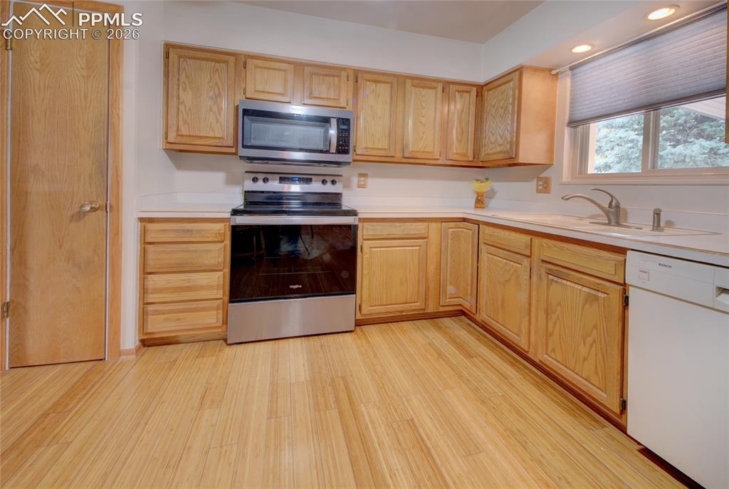 Image 14 of 33: Kitchen featuring wood-finish flooring, wood cabinetry, stainless steel ran