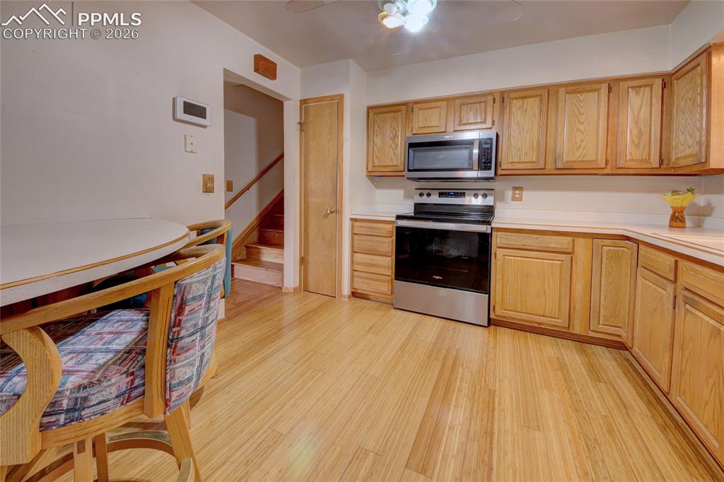 Image 15 of 33: Kitchen featuring wood-finish flooring, light-toned wood cabinetry, built-i