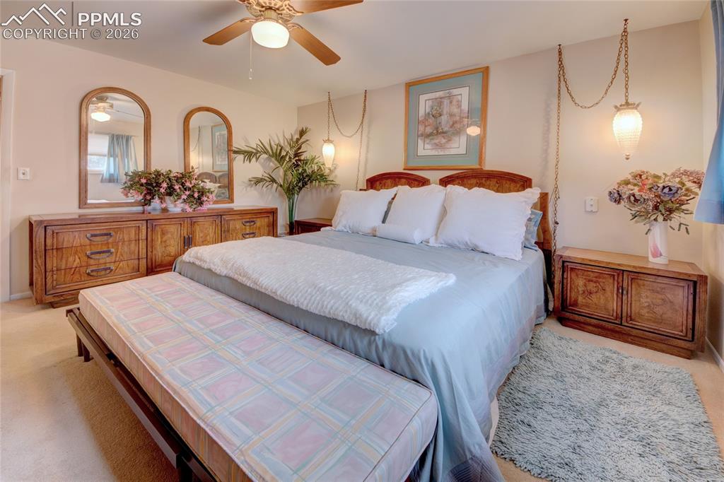Image 18 of 33: Carpeted bedroom featuring a wooden bed frame, ceiling fan, and built-in wa
