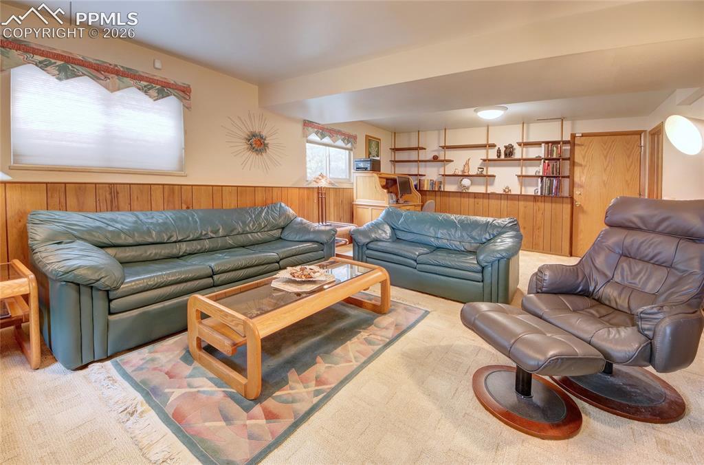 Image 24 of 33: Finished lower level featuring wood paneling, built-in shelving, carpet flo