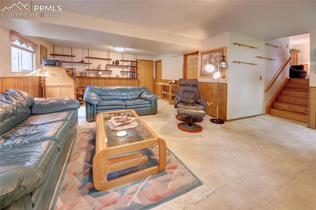 Image 27 of 33: Spacious carpeted room featuring extensive wood paneling and built-in shelv