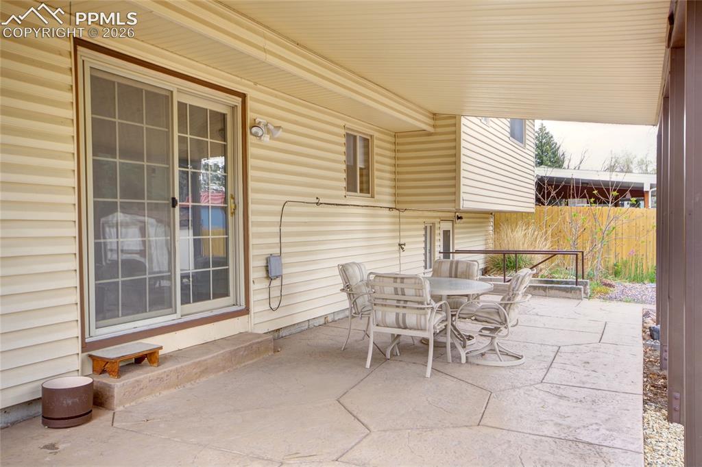 Image 28 of 33: Covered patio featuring a stamped concrete surface and a sliding glass door