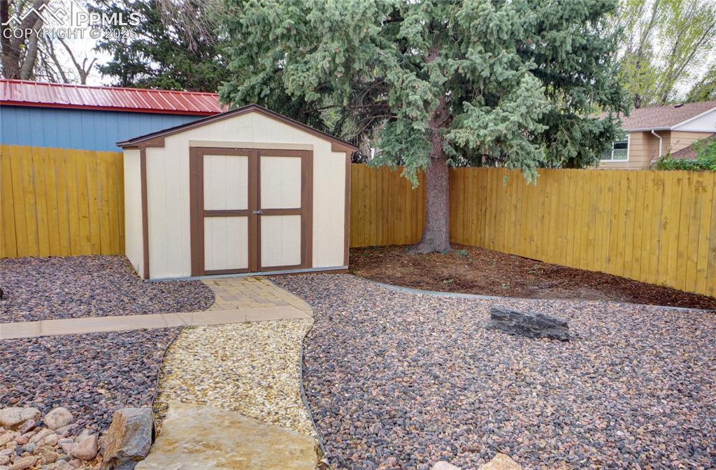 Image 31 of 33: Backyard featuring a functional storage shed with double doors, a curved pa