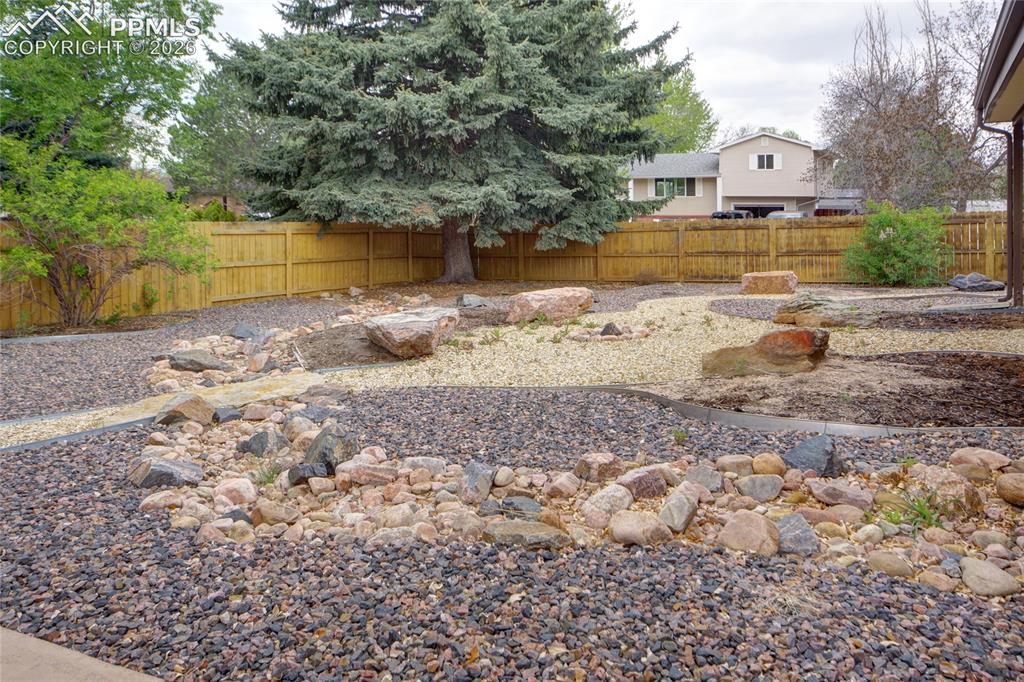 Image 33 of 33: Landscaped backyard featuring decorative rock beds, large accent boulders, 