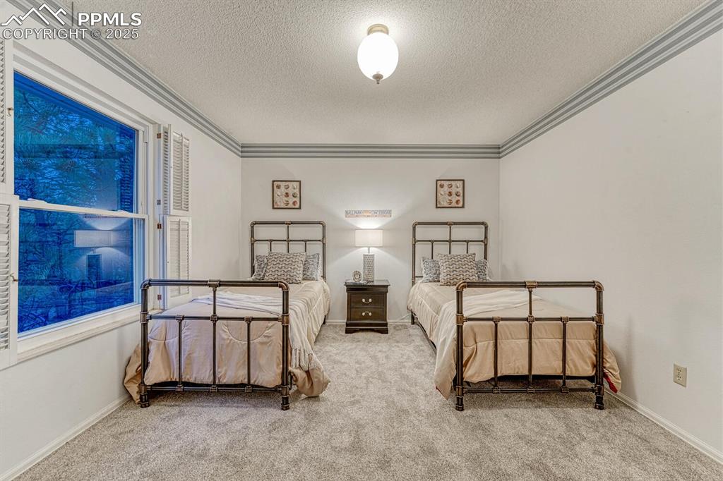 Image 29 of 50: Upper Level Bedroom #2 has neutral carpet and crown molding.