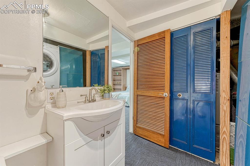 Image 40 of 50: The Basement Shower Bathroom has a vanity, mirror, shower, and laundry area