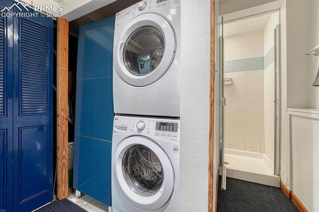 Image 41 of 50: Stackable washer and dryer and tiled shower in the Basement Bathroom.