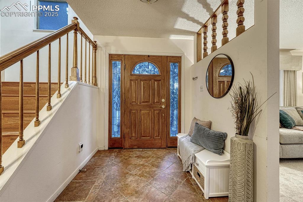 Image 7 of 50: Front Entry with tile floor and gorgeous wood front door with stained glass