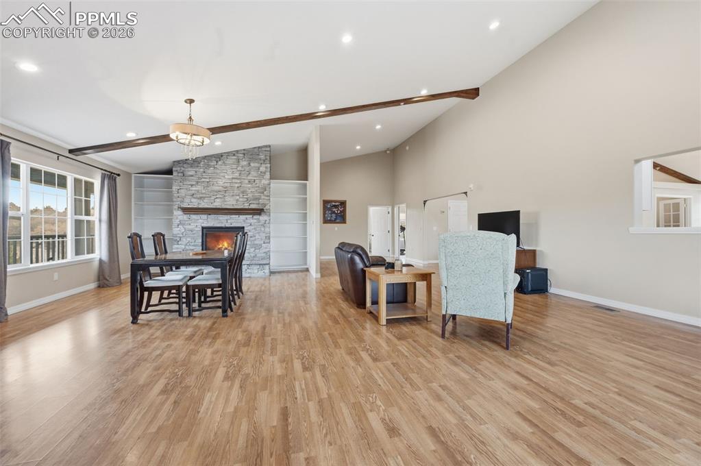 Image 6 of 50: Great room with a stone fireplace and builtins. On the right is a large din