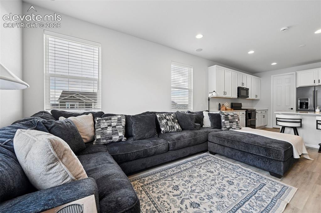 Image 10 of 31: Open-concept living area with wood-finish flooring, recessed lighting, and