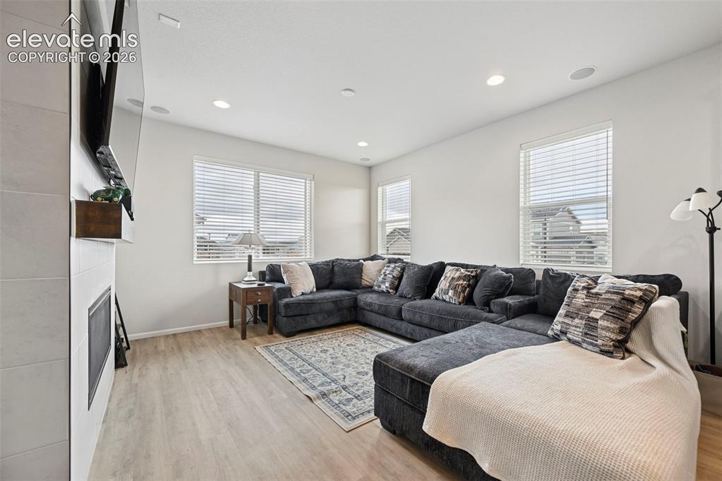 Image 12 of 31: Living area featuring a tiled fireplace surround with a wood mantel, light