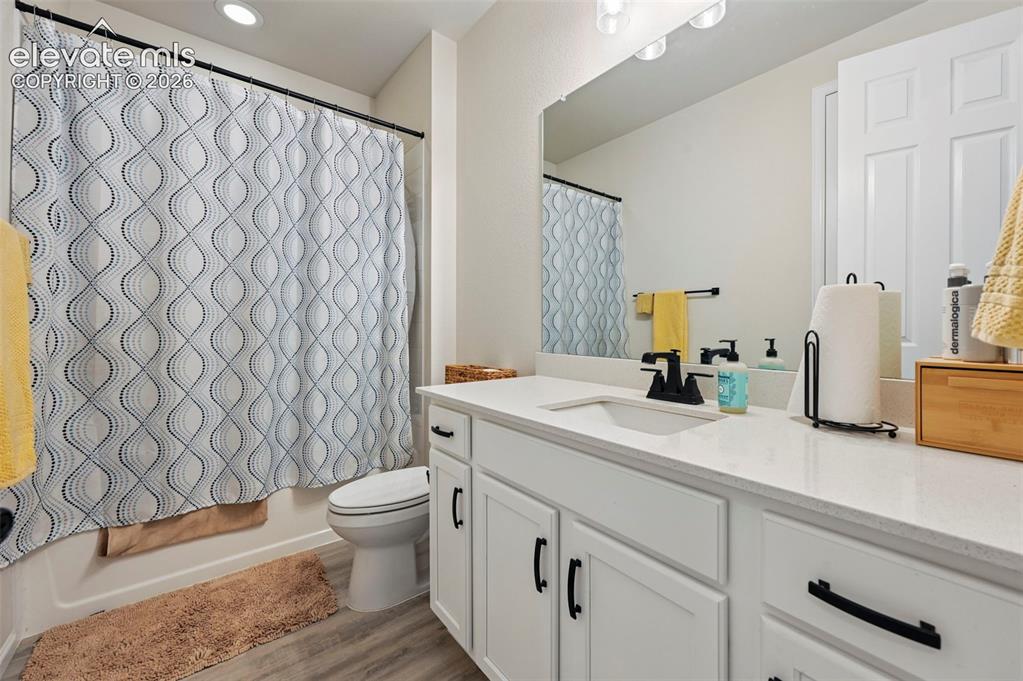 Image 18 of 31: White vanity with a light-colored countertop, undermount sink, and black fa