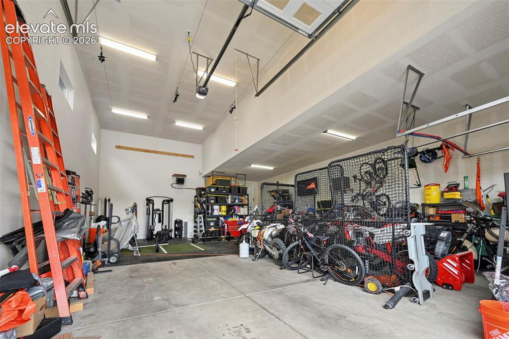 Image 2 of 31: Spacious garage with high ceilings, multiple fluorescent light fixtures, an