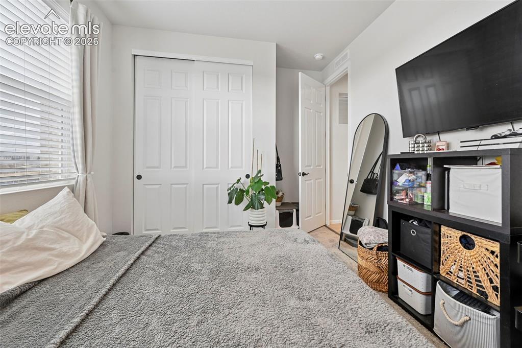 Image 22 of 31: Window with white horizontal blinds, white bifold closet doors, and light-c