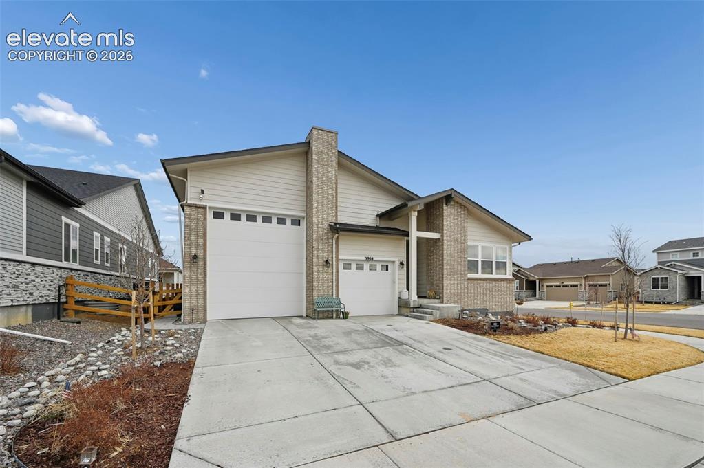 Image 29 of 31: Siding exterior with brick accents, attached two-car garage, concrete drive