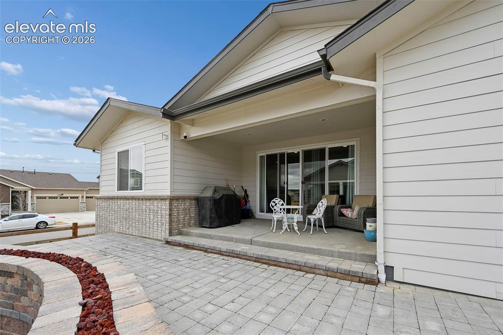 Image 30 of 31: Covered patio with concrete flooring, accented by a light brick facade and