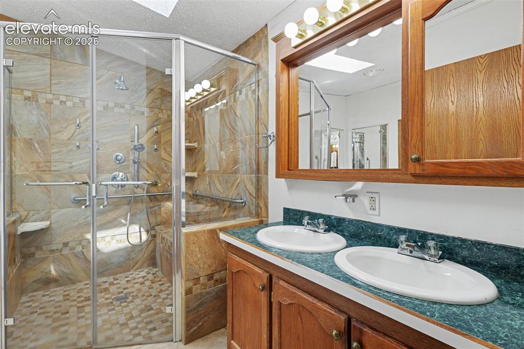 Image 14 of 26: Tiled walk-in shower with glass enclosure and multiple shower heads