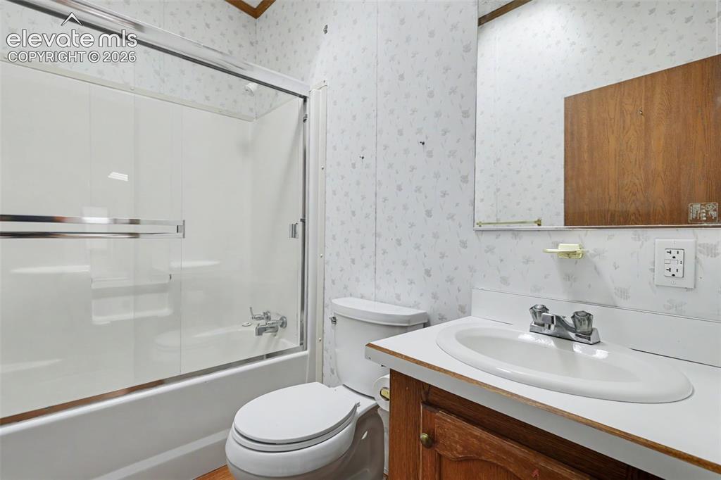 Image 16 of 26: Bathroom featuring a white bathtub with sliding glass doors and a chrome fa