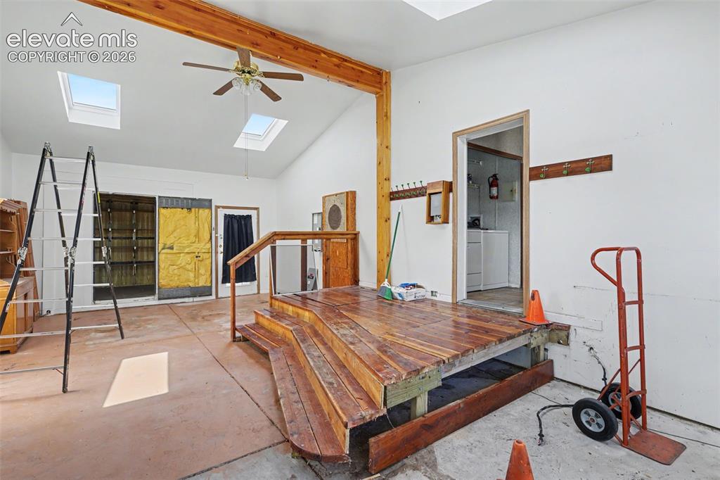 Image 19 of 26: Room featuring vaulted ceilings with exposed wood beam, two skylights, a ce