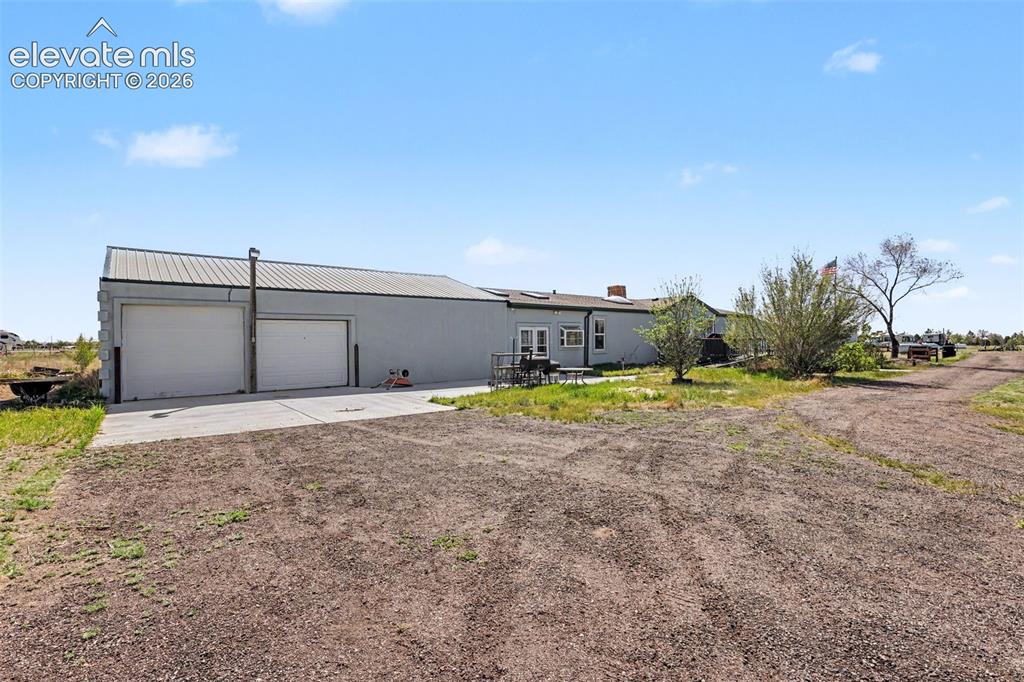 Image 2 of 26: Expansive detached garage with two overhead doors and a metal roof