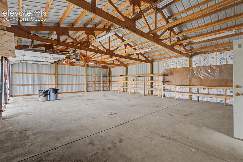 Image 22 of 26: Spacious outbuilding featuring exposed wood trusses, corrugated metal roofi