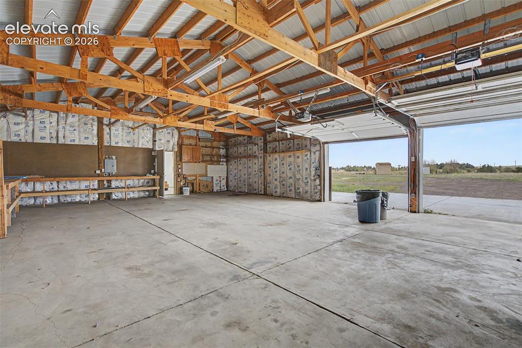Image 23 of 26: Spacious utility building featuring a concrete floor, exposed wood beam cei