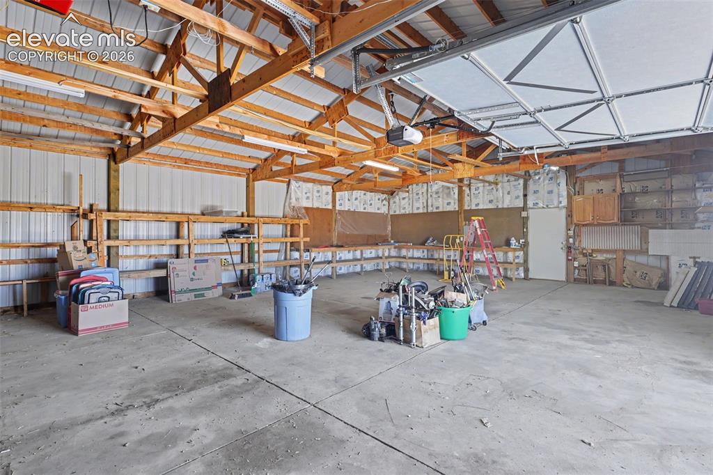 Image 24 of 26: Spacious workshop featuring a concrete floor, exposed wood beam ceiling, co