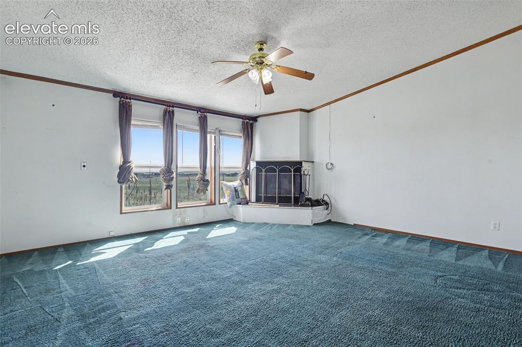 Image 7 of 26: Spacious interior featuring a corner fireplace with a white hearth, multipl