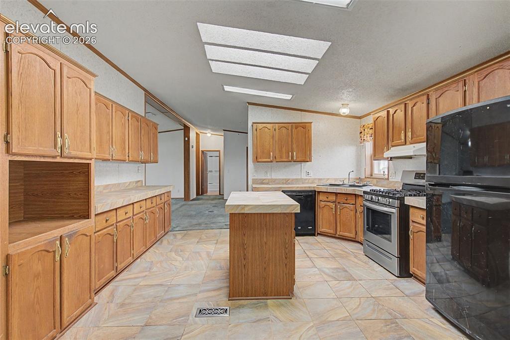 Image 9 of 26: Kitchen featuring extensive wood cabinetry, a central island, tile flooring