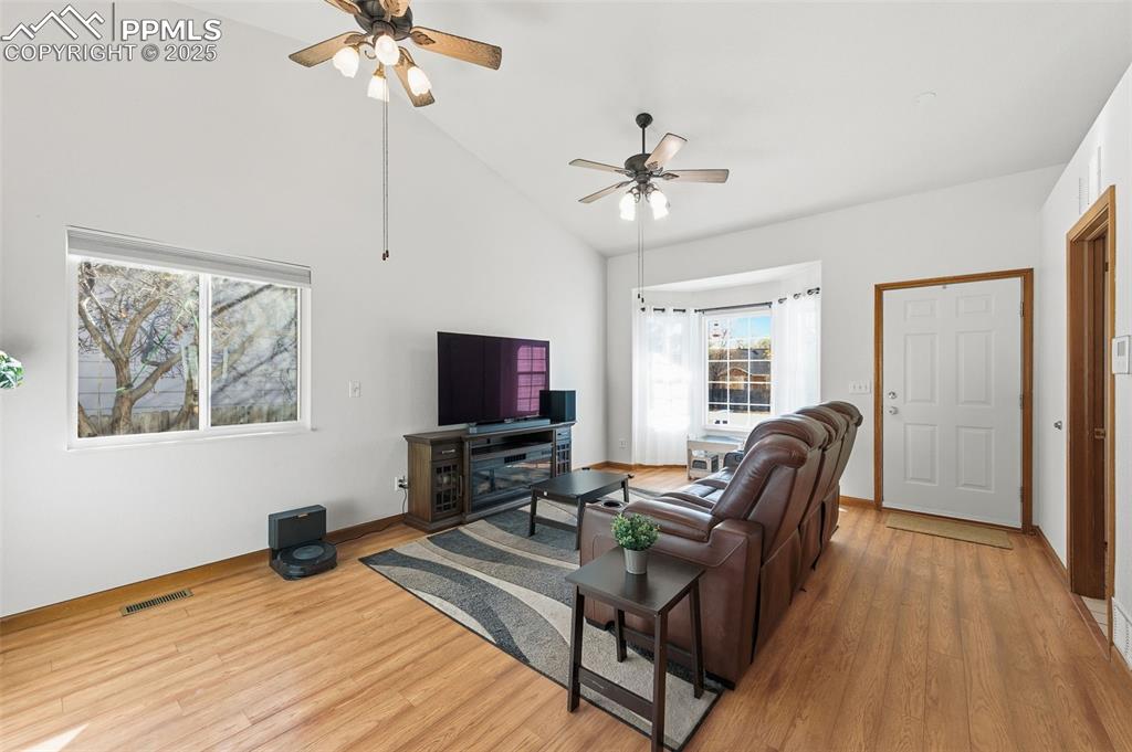 Image 4 of 32: Large living room with vaulted ceilings and hardwood floors